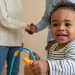 parents shaking hands with a happy smiling child in the foreground