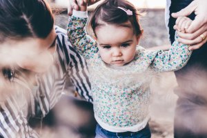 Parents holding child hands whilst she tries to walk