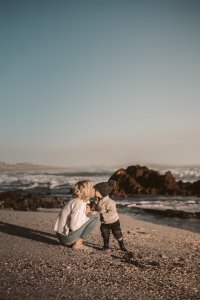 Mum and child on beach, mum leant down to give child a kiss