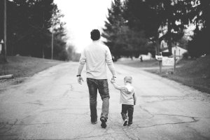 black and white picture of father and son holding hands walking away
