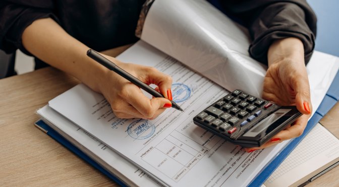 lady holding pen and calculator making notes in a book