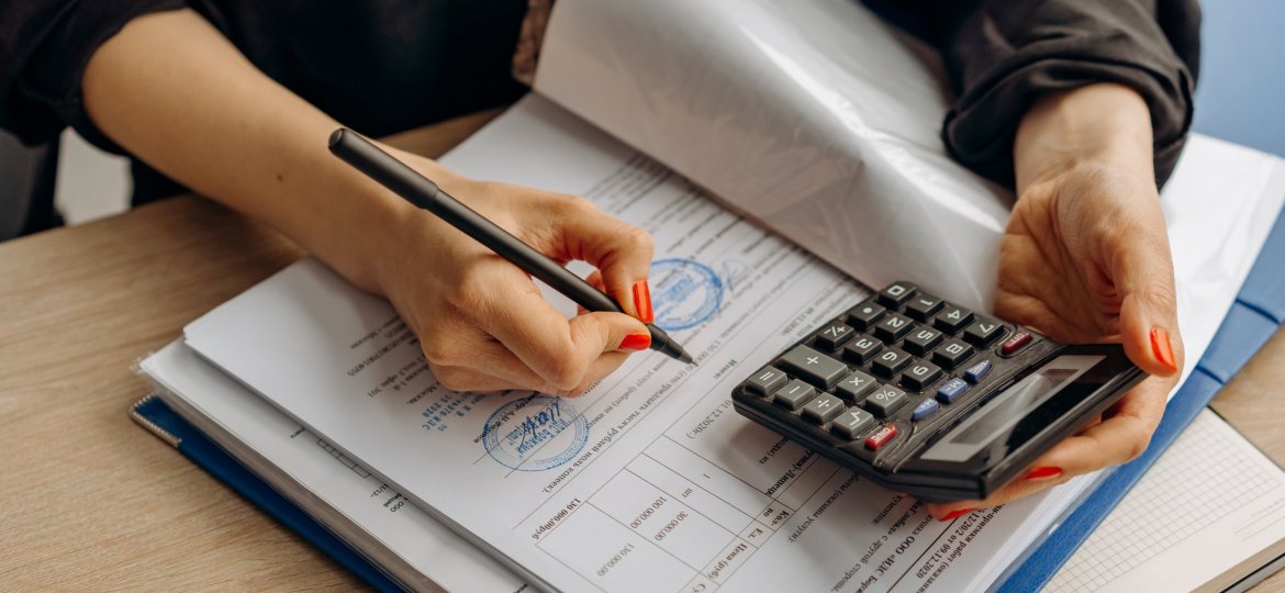 lady holding pen and calculator making notes in a book