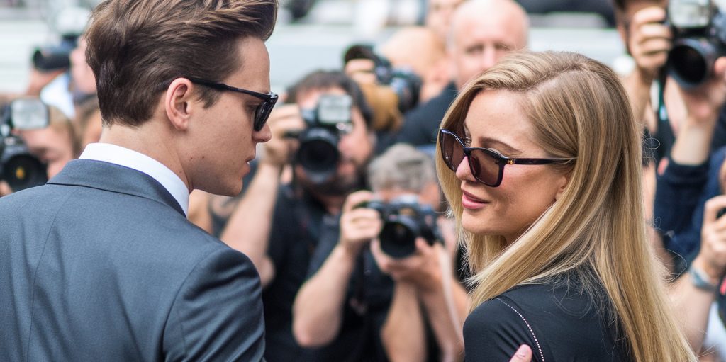 Celebrity couple wearing sunglasses being photographed by paparazzi
