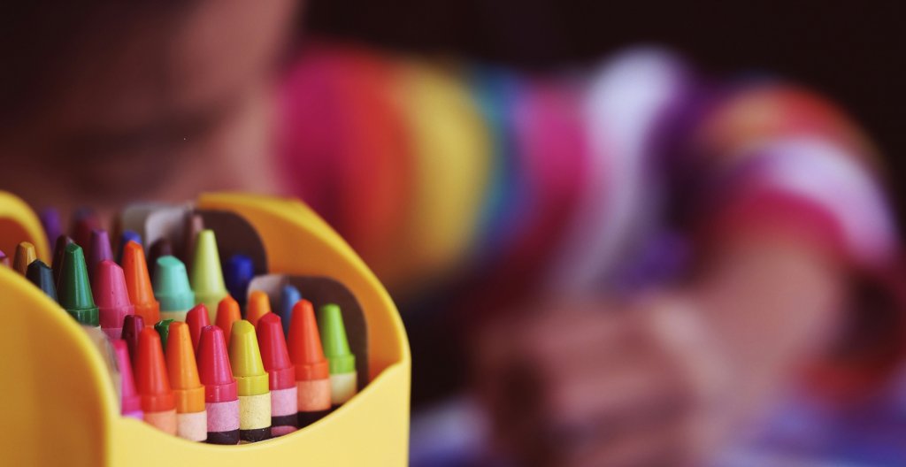 Child colouring with crayons