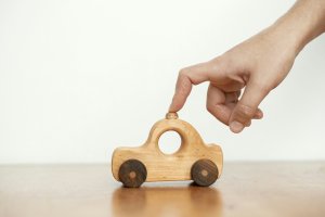 hand pushing a small wooden car