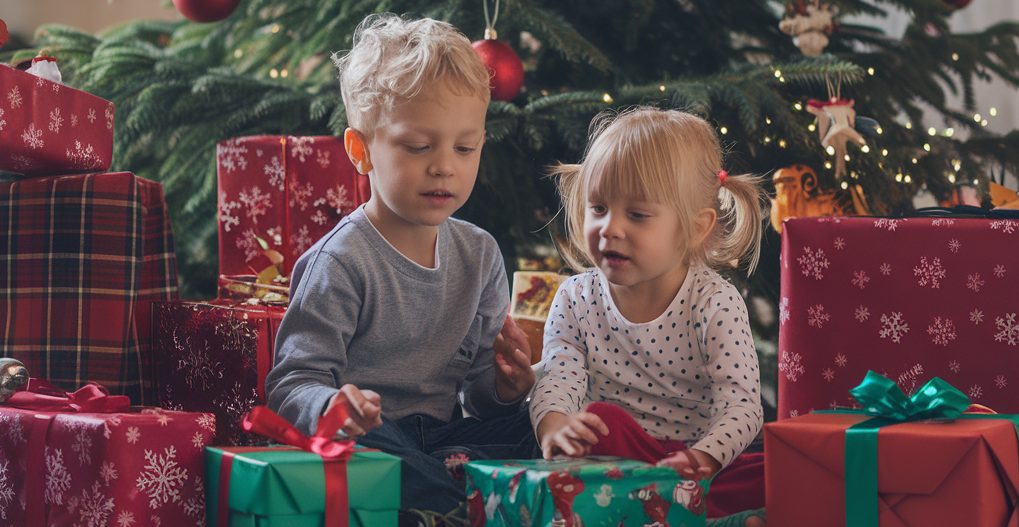 a-photo-of-children-sitting-in-front-of-a-christmas-tree