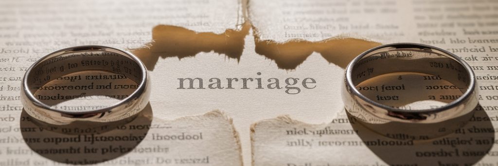 two wedding rings with the word marriage torn in a book.