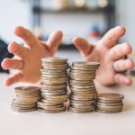 a pile of coins with two hands dividing it up